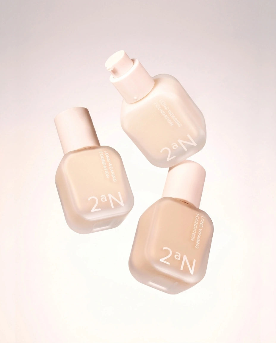 Three 2aN liquid foundation bottles in a soft warm beige shade, floating against a clean off-white background.