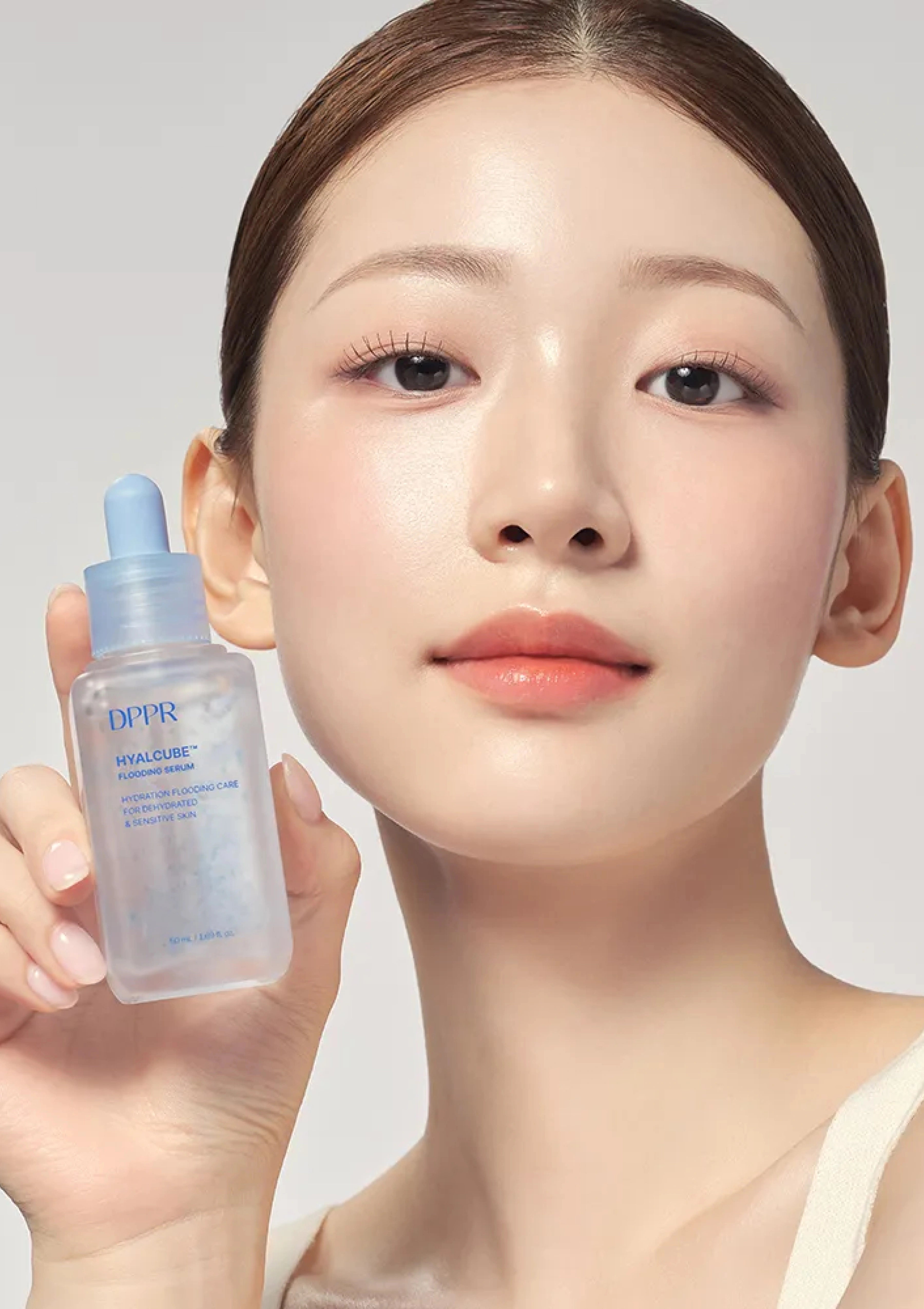Woman holding a skincare serum bottle with a neutral background