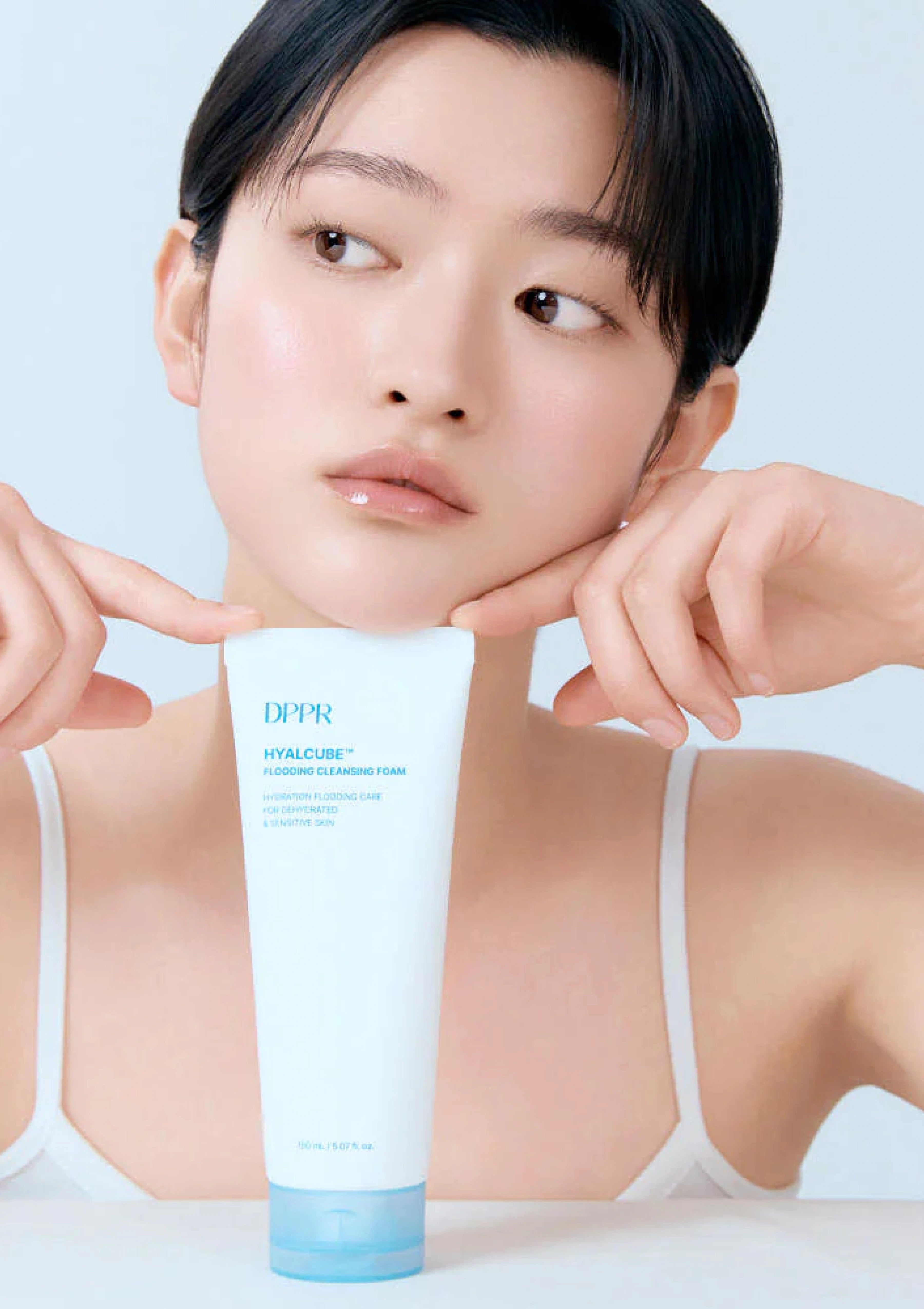 Woman holding a DPPR skincare product against a light background