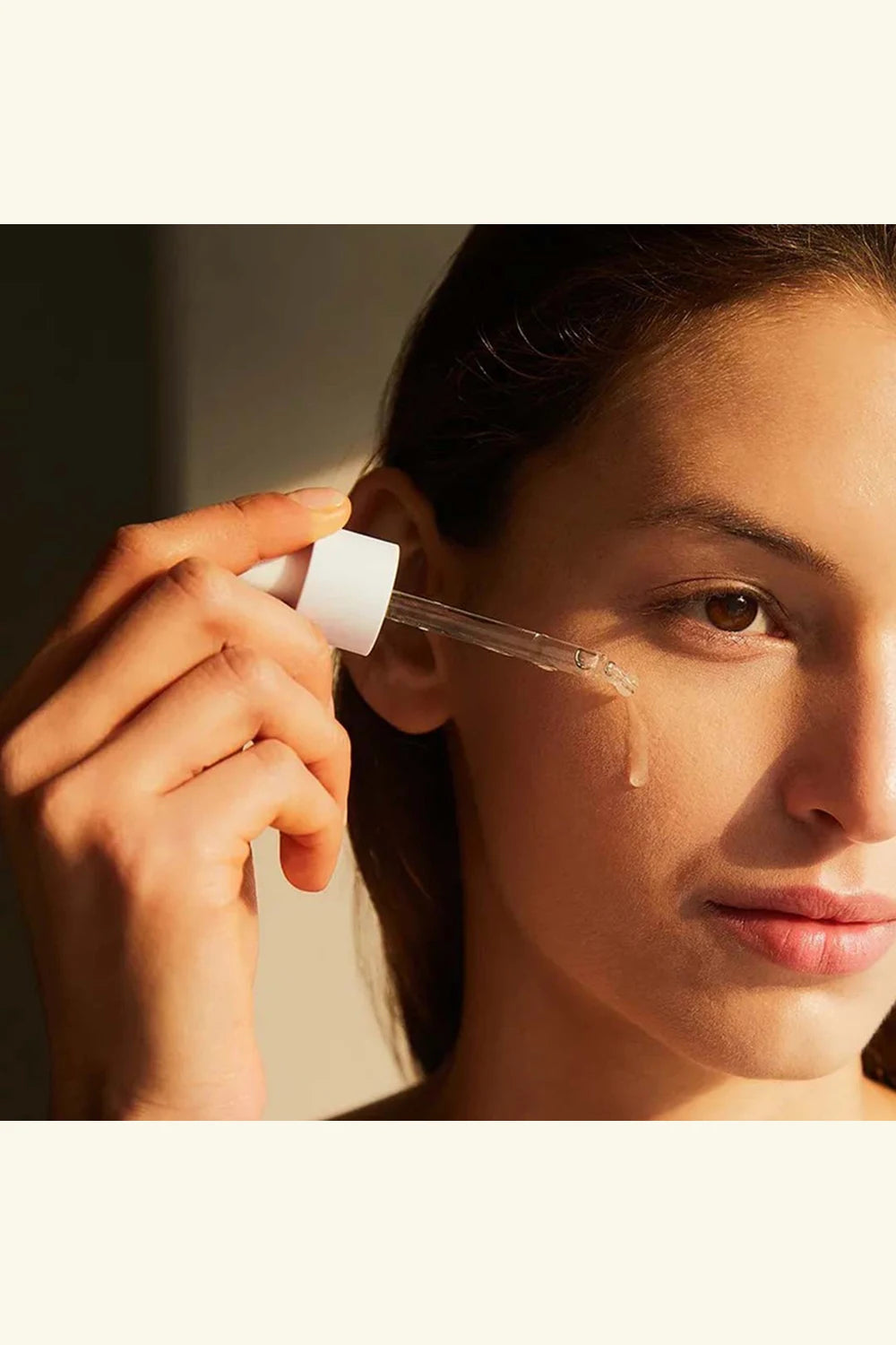 Person applying a clear liquid to their ear with a dropper.