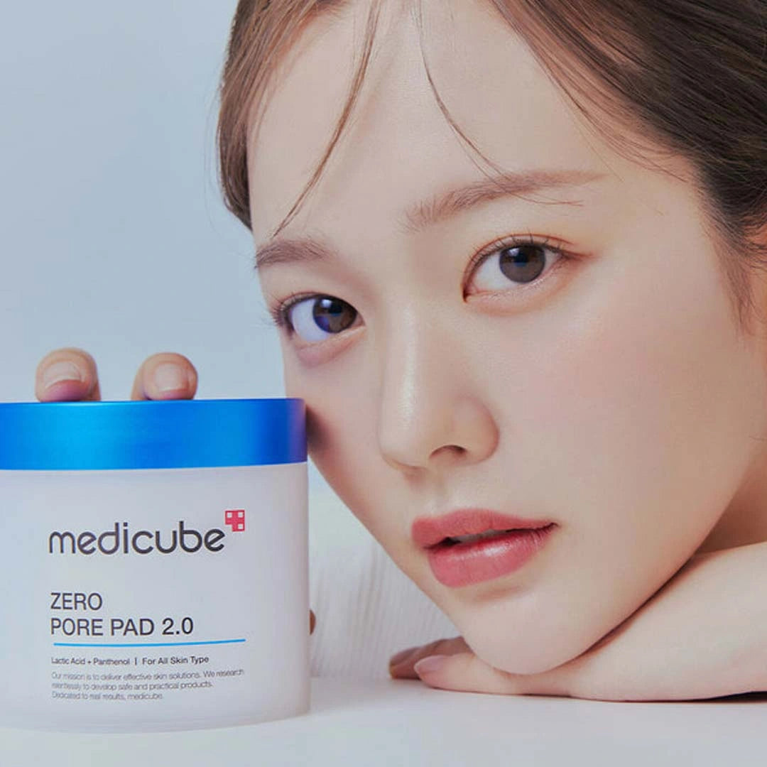 Woman holding a Medicube Zero Pore Pad 2.0 product with a plain background