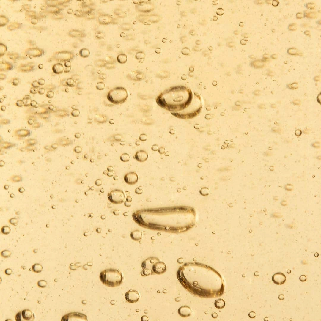 Close-up of oil droplets on a yellow liquid surface