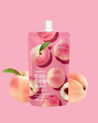 A pink stand-up pouch of sugarbaba peach jelly with illustrations of peaches and a white cap, centered on a pink background with whole and sliced peaches around it.
