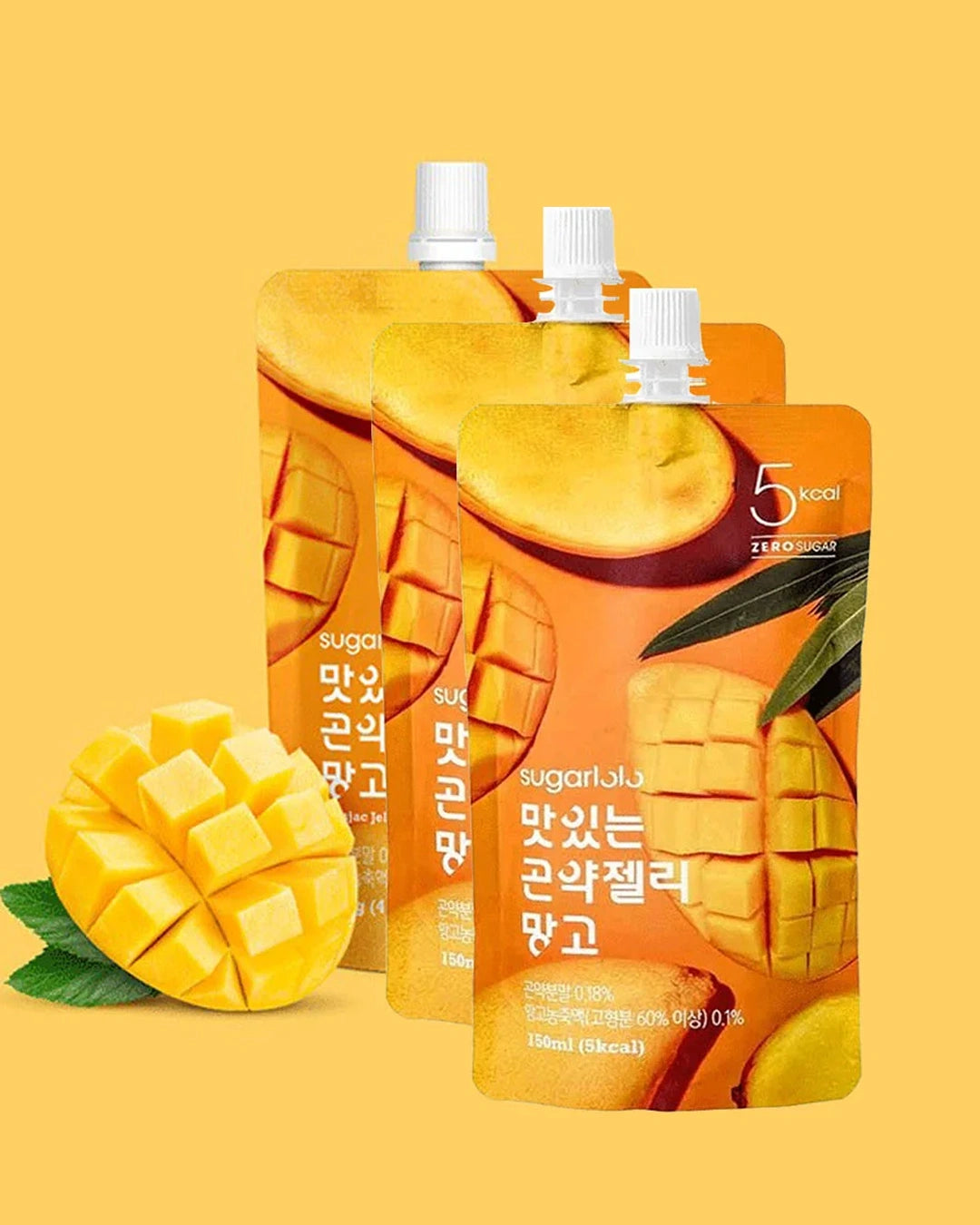 Three stand-up pouches of sugarbula mango-flavored drink with white spout caps, arranged in a fan shape on a warm yellow background, with a sliced mango and green leaves at the lower left.