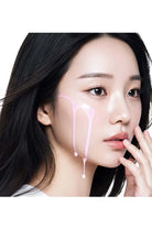 Woman with black hair and minimal makeup, holding her chin with one hand.