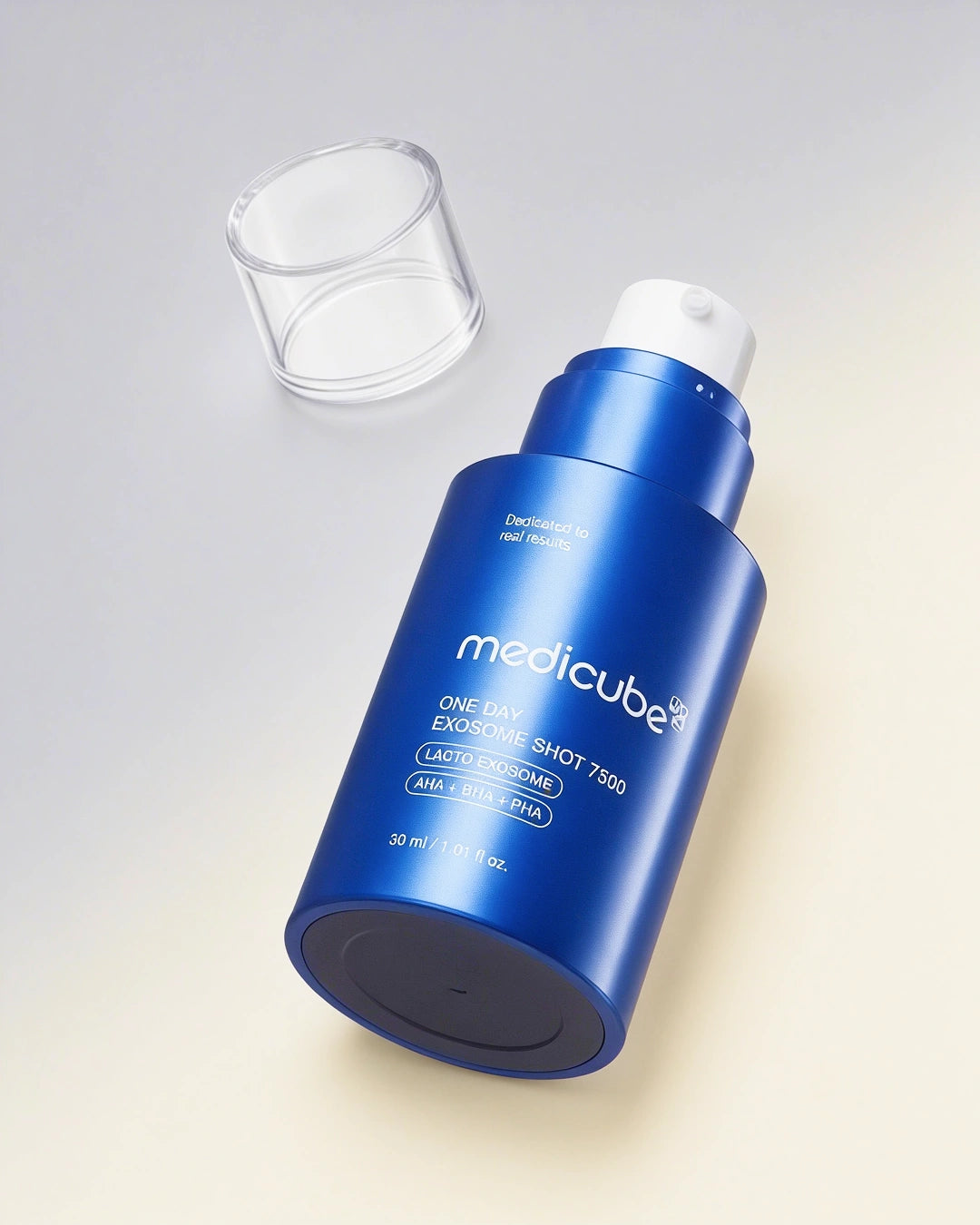 A metallic blue bottle of medicube One Day Exosome Shot 7500 with a white pump dispenser, shown with its clear cap off on a light beige background.