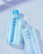 Two clear bottles of DPPR Hyalcube Flooding Toner with blue caps, arranged on a pale blue surface with water droplets and a smear of toner visible.