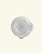 A translucent white plastic lid with a small integrated handle, shown from a top-down view on a solid cream background.