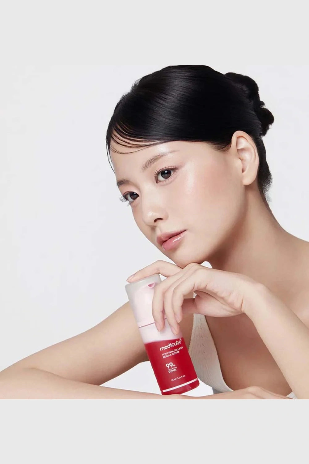 Woman holding a red and white skincare product against a white background