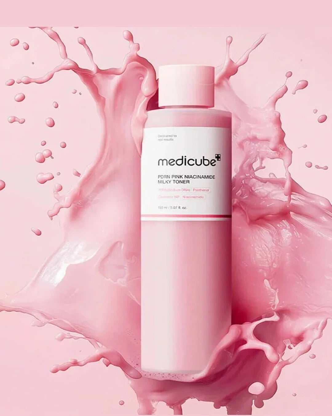 A bottle of medicube+ Body Pink Macadamie Milky Toner centered against a pink background with a large pink liquid splash behind it.