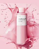 A bottle of medicube+ Body Pink Macadamie Milky Toner centered against a pink background with a large pink liquid splash behind it.