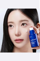 Woman applying Medicube skincare product to her face against a white background