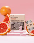 NE:AR Niaro Biker shoes packaging box displayed with grapefruit slices and whole grapefruit on a pink background.