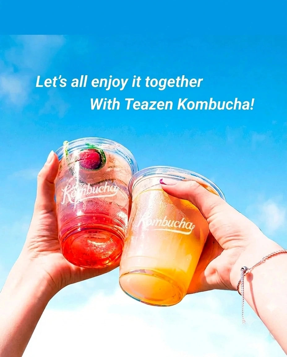 Two hands holding clear plastic cups filled with colorful tea-based drinks, one red and one orange, against a bright blue sky background. White text at the top reads, 'Let's all enjoy it together With Teazen Kombucha!'.