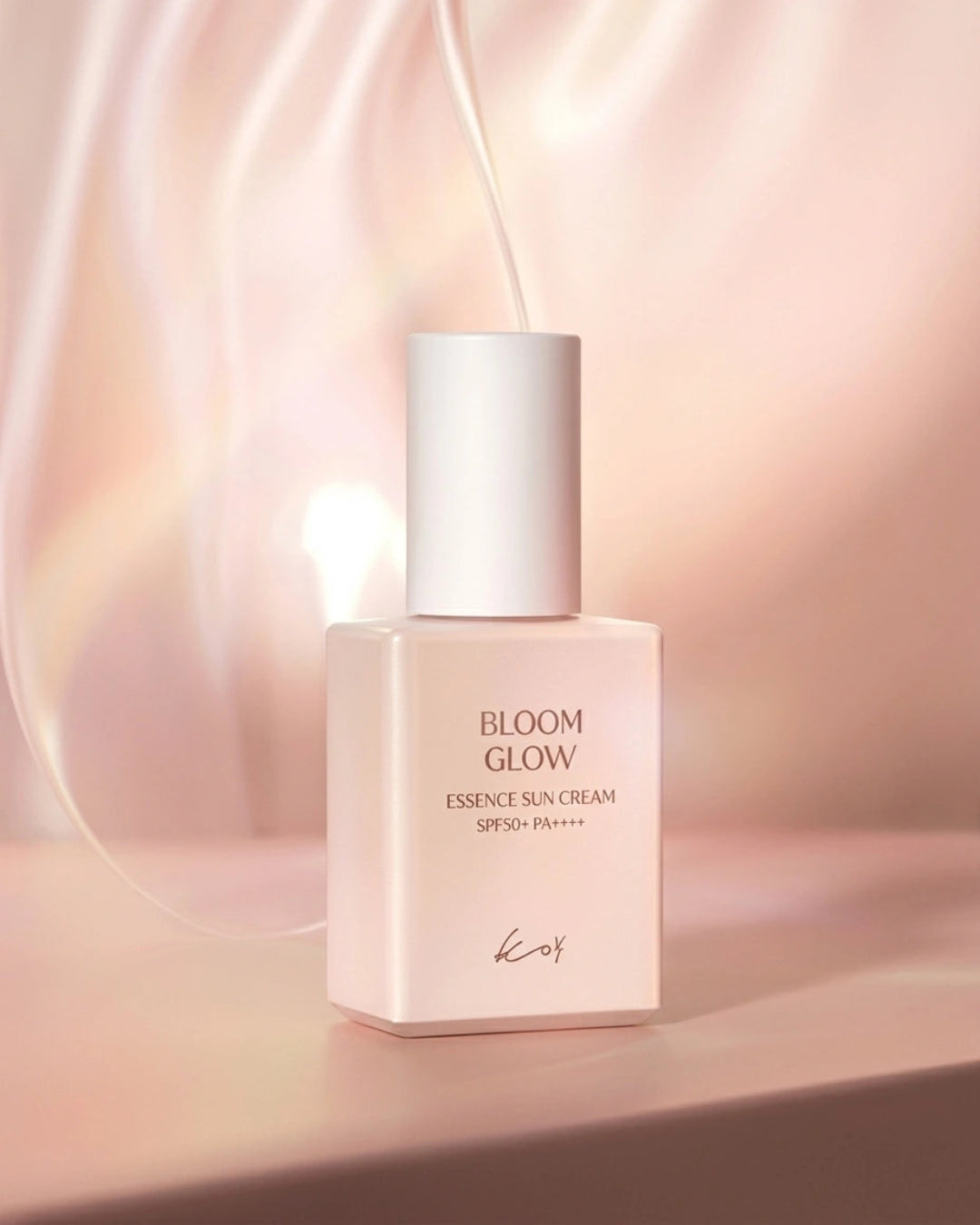 A square bottle of Kows Bloom Glow Essence Sun Cream SPF30 PA++++ with a white cap, set against a soft, warm pink and beige background with elegant light streaks.