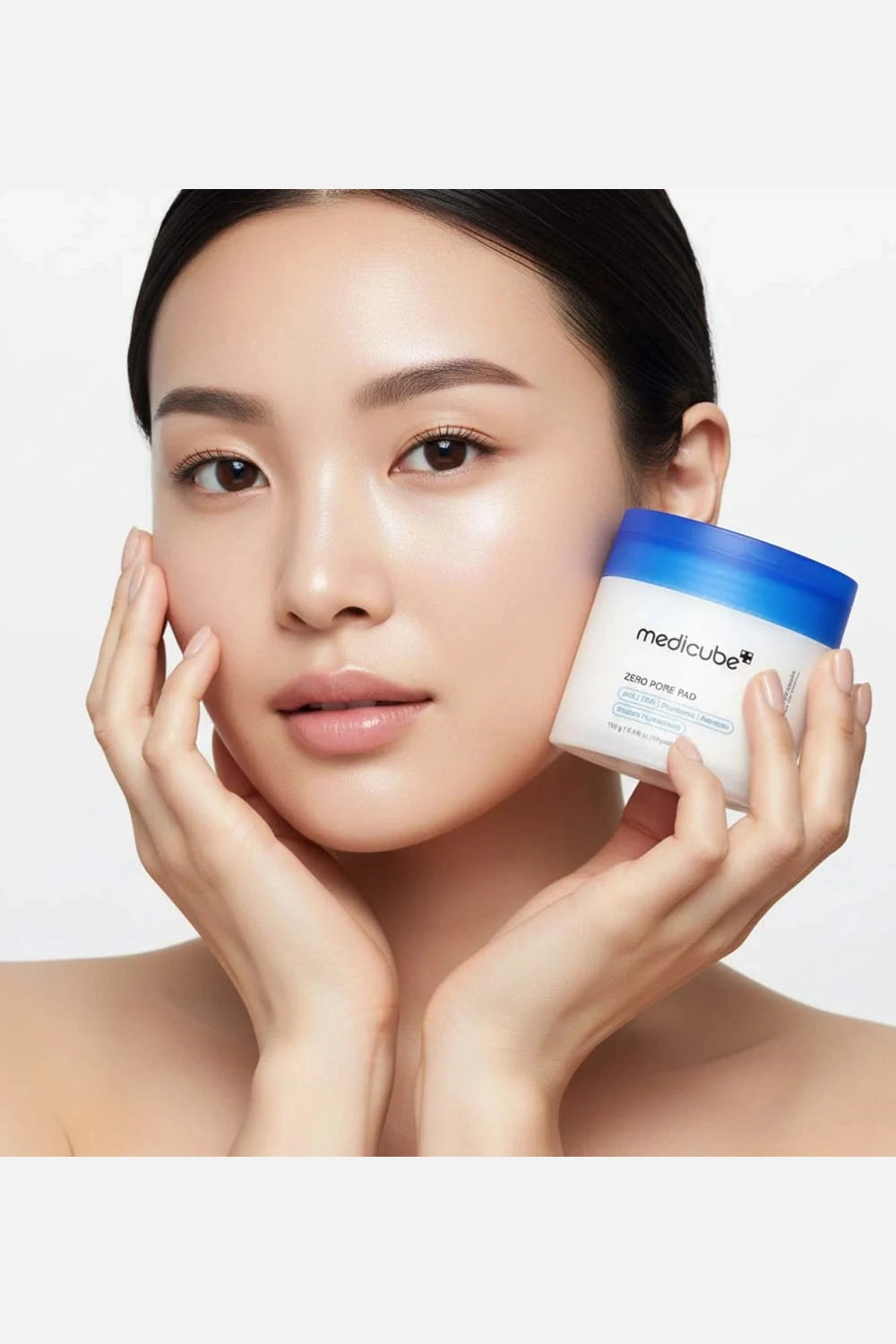 Woman holding a jar of Medicube skincare product against a plain background