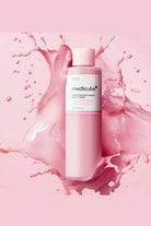 Medicube skincare product with pink splash on a pink background