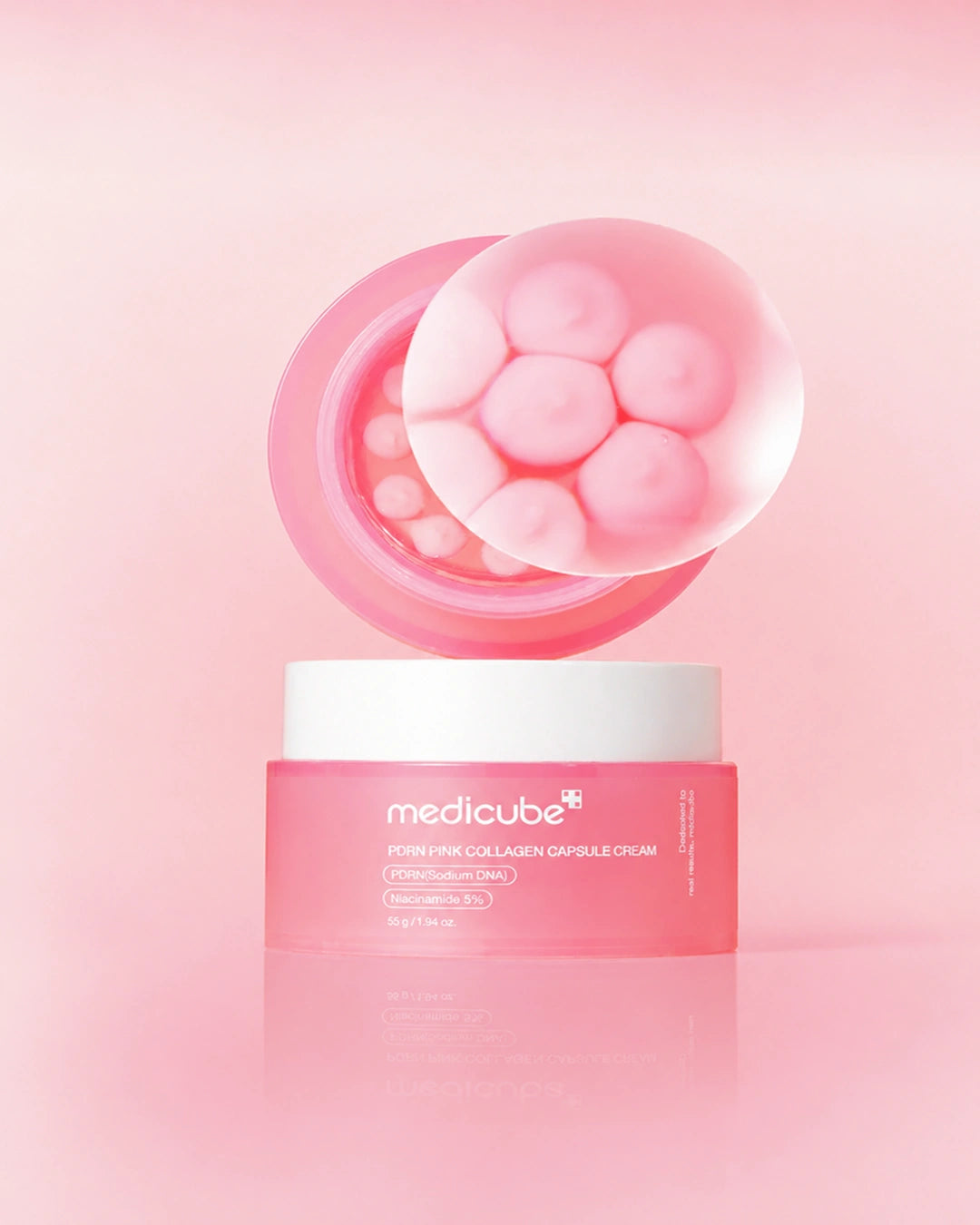Medicube Poyi Pink Collagen Capsule Cream in a pink jar with a white lid, shown with a floating transparent bubble containing pink capsule-like spheres on a soft pink background.