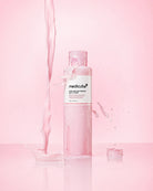 A bottle of medicube Ultra Fine Emulsion Clean Toner with a pink liquid inside, set against a pink background with a pink liquid splash and droplets.