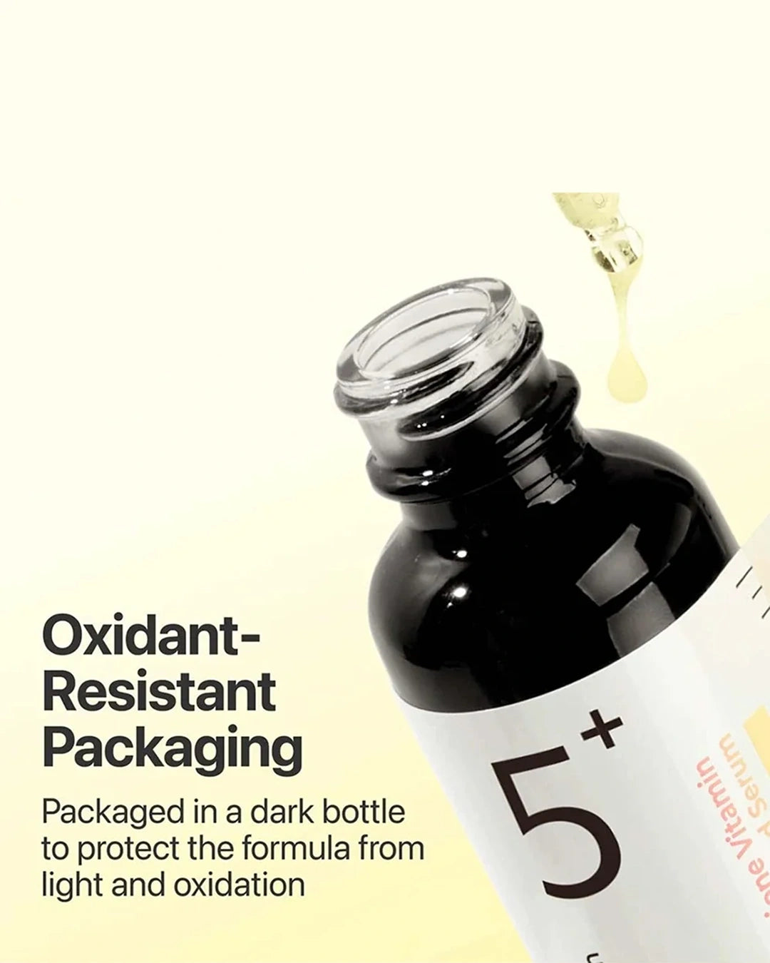 A close-up of a dark bottle with a white label reading '5+' and partial text 'Vitamin S', shown with a drop of yellow liquid above the open neck and marketing text on a pale cream background.