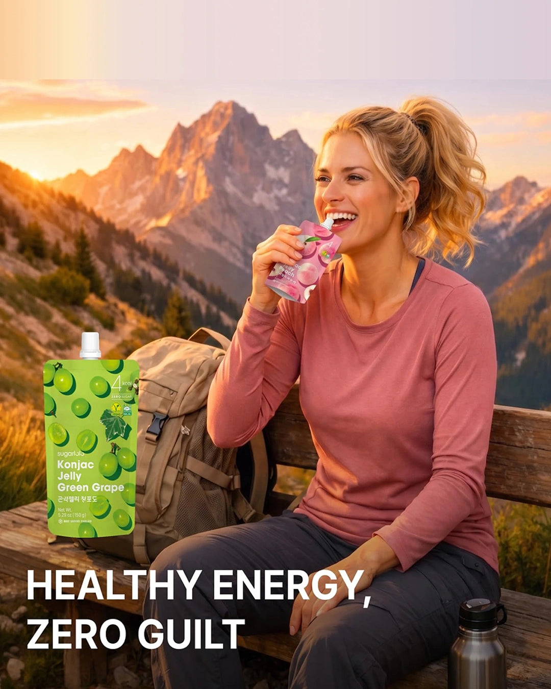 A woman sitting on a wooden bench in front of a mountain landscape at sunset, drinking from a pink reusable bottle. A green juice pouch labeled Kambo Jelly Green Grape is shown beside her, with the text 'HEALTHY ENERGY, ZERO GUILT' at the bottom.
