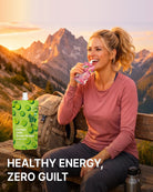 A woman sitting on a wooden bench in front of a mountain landscape at sunset, drinking from a pink reusable bottle. A green juice pouch labeled Kambo Jelly Green Grape is shown beside her, with the text 'HEALTHY ENERGY, ZERO GUILT' at the bottom.