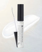 HONEST Eyelash Serum in a clear cylindrical bottle with a black cap, shown with the applicator wand and a black cap piece on a soft white background.