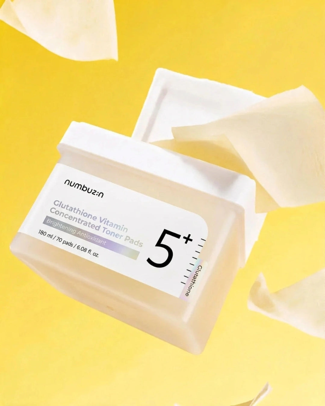 Numbuen Glutathione Vitamin Concentrated Toner Pads jar with its lid off, set against a bright yellow background with floating white sheet-like elements.