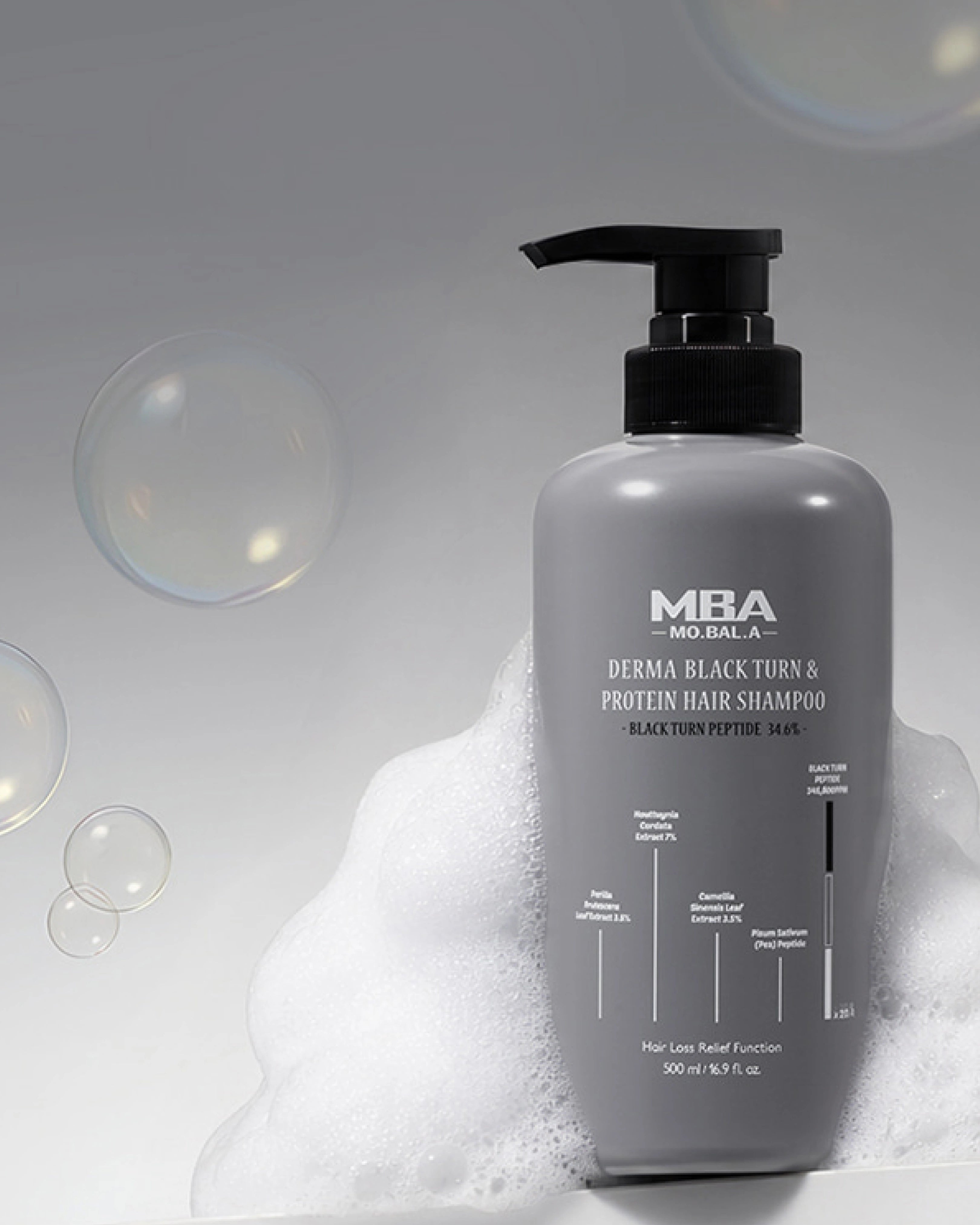A gray pump bottle of MBA Derma Black Tunic & Protein Hair Shampoo, styled with white foam and floating bubbles against a light gray background.
