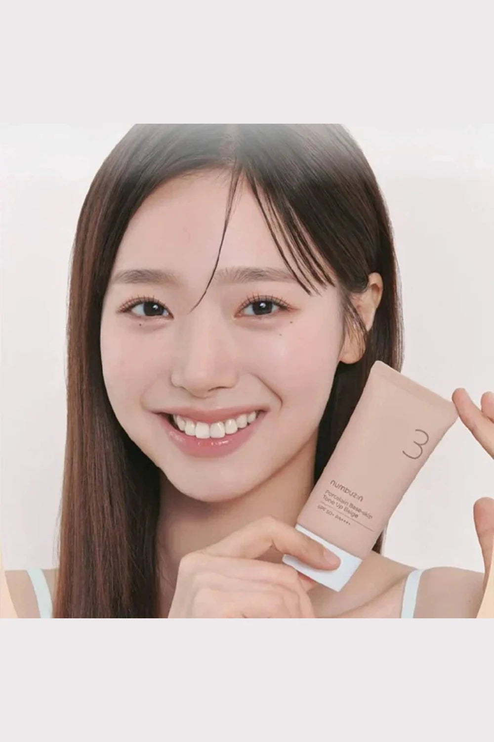 Woman holding a skincare product against a plain background