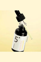 Bottle of skincare serum with dropper on a beige background