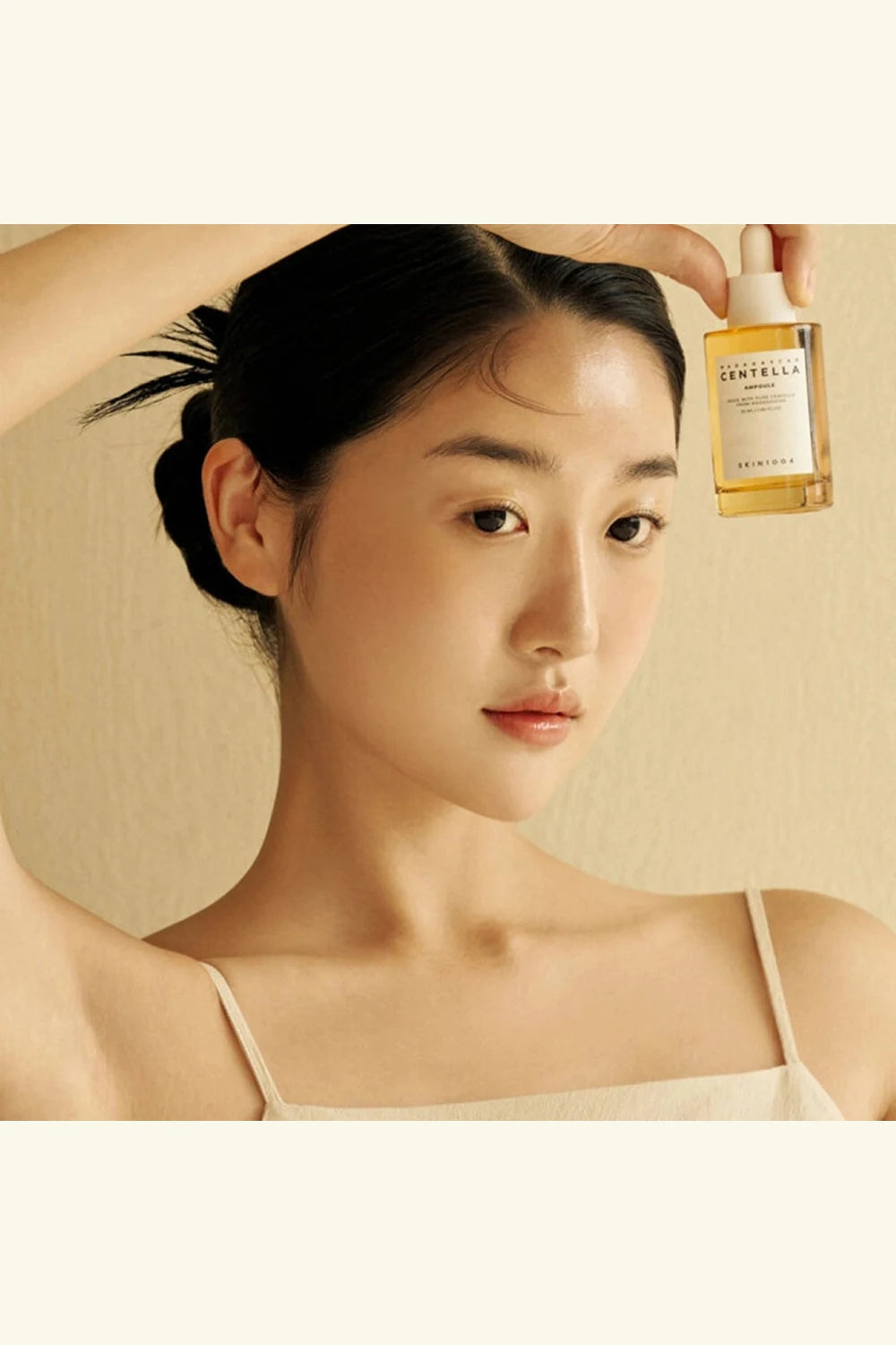 Woman holding a bottle of skincare product with a neutral background