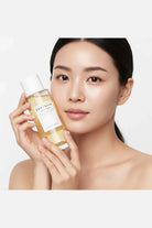 Woman holding a bottle of skincare product with a plain background