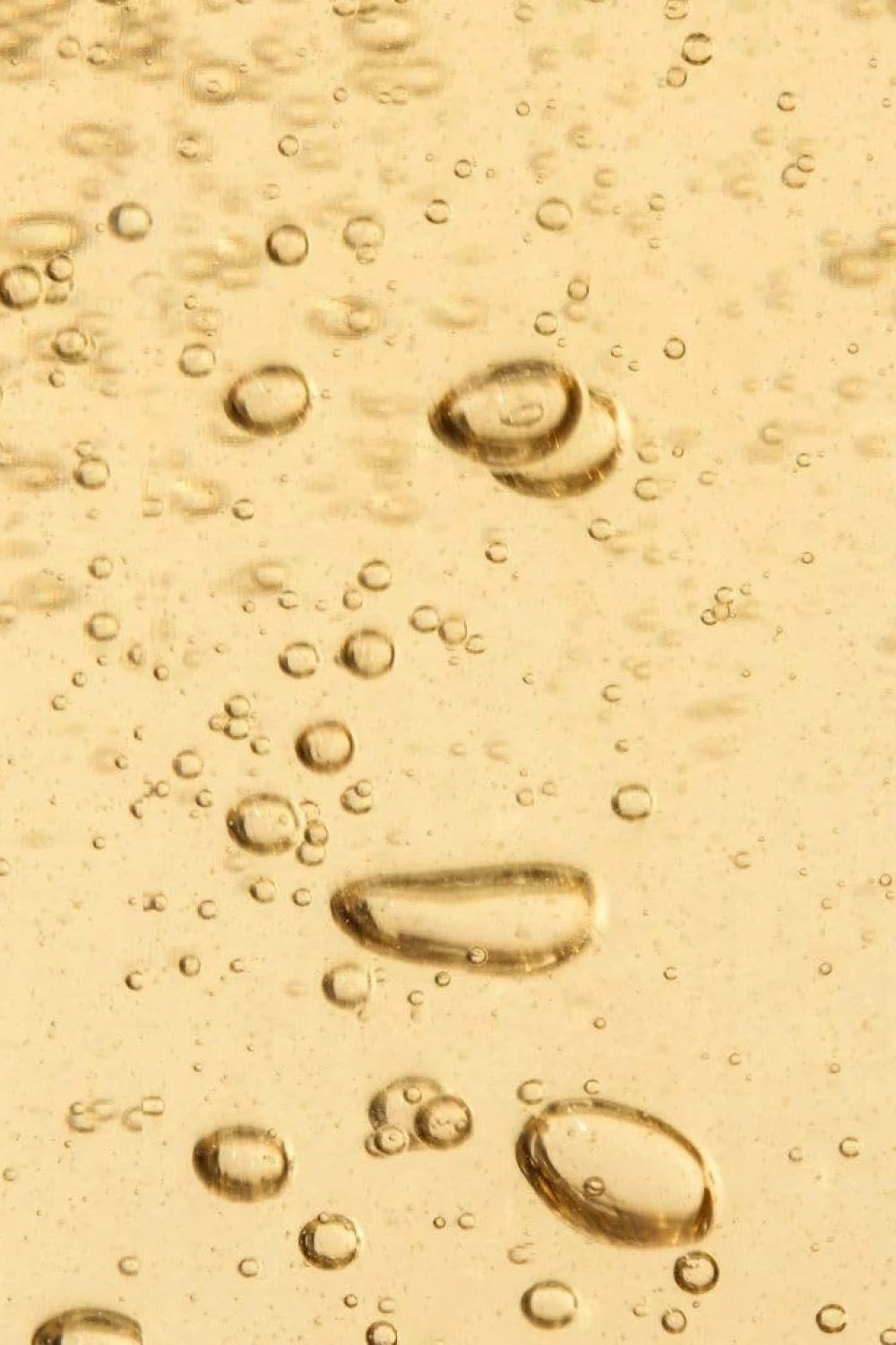 Close-up of oil droplets on a yellowish liquid surface