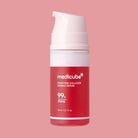 Red skincare serum bottle with white pump on a pink background