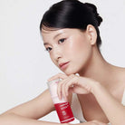 Woman holding a red skincare product with a white background