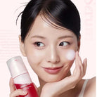 Woman applying cream to her face with a bottle of Medic� on a pink background