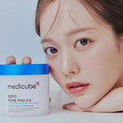 Woman holding a Medicube Zero Pore Pad 2.0 product with a plain background