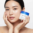 Woman holding a jar of Medicube skincare product against a white background