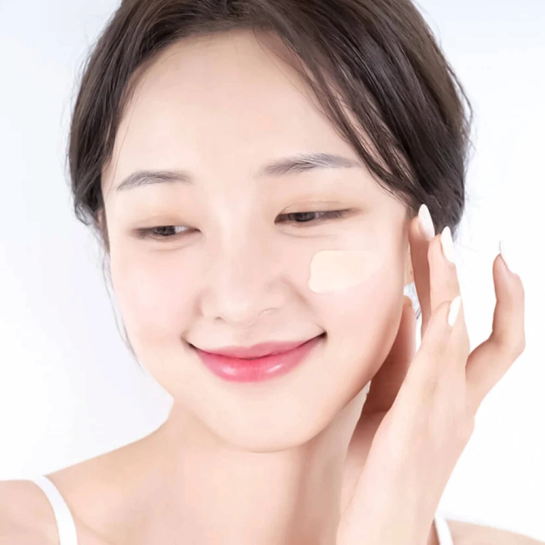 Woman applying cream to her face on a white background