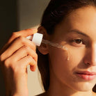 Person applying a dropper of liquid to their face