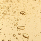 Close-up of oil droplets on a yellow liquid surface