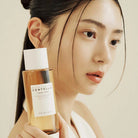 Woman holding a bottle of Skinceed Centella product against a neutral background