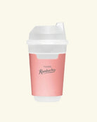 A reusable travel tumbler with a pink body and a white lid, featuring the brand name 'TEAZEN' and 'Kombucha' printed on the front, set against a solid cream background.