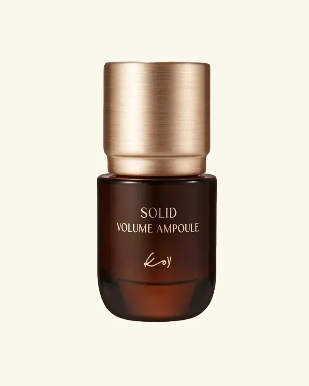 A single cosmetic solid ampoule bottle with a brushed metallic rose gold cap and a dark amber-brown glass body, centered on a warm off-white background. The bottle is labeled 'SOLID VOLUME AMPoule' with the brand name 'Koy' printed below.