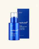 A blue Medicube skincare bottle with a clear cap stands in front of a matching blue product box on a light cream background. Visible text includes Medicube and One Day Exosome Shot 2000.