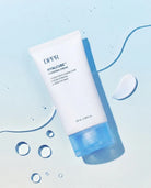 A white tube of DPPR Hyalcube Flasking Cream with a translucent blue cap, styled diagonally on a light blue background with decorative water droplets and a smear of cream.